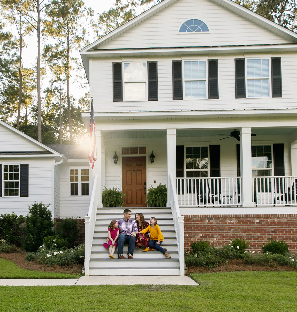 Family sitting outside their home, home insurance